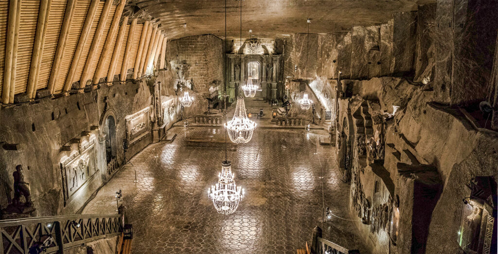 Grand hall in Wieliczka Salt Mine, Poland, featuring chandeliers and intricate salt carvings.